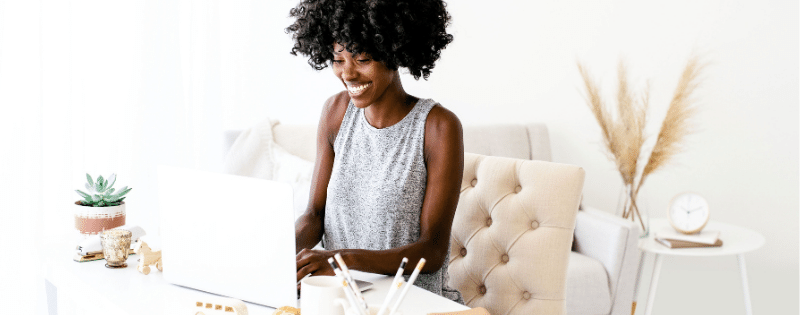 woman with curly hair sitting in a pink chair typing