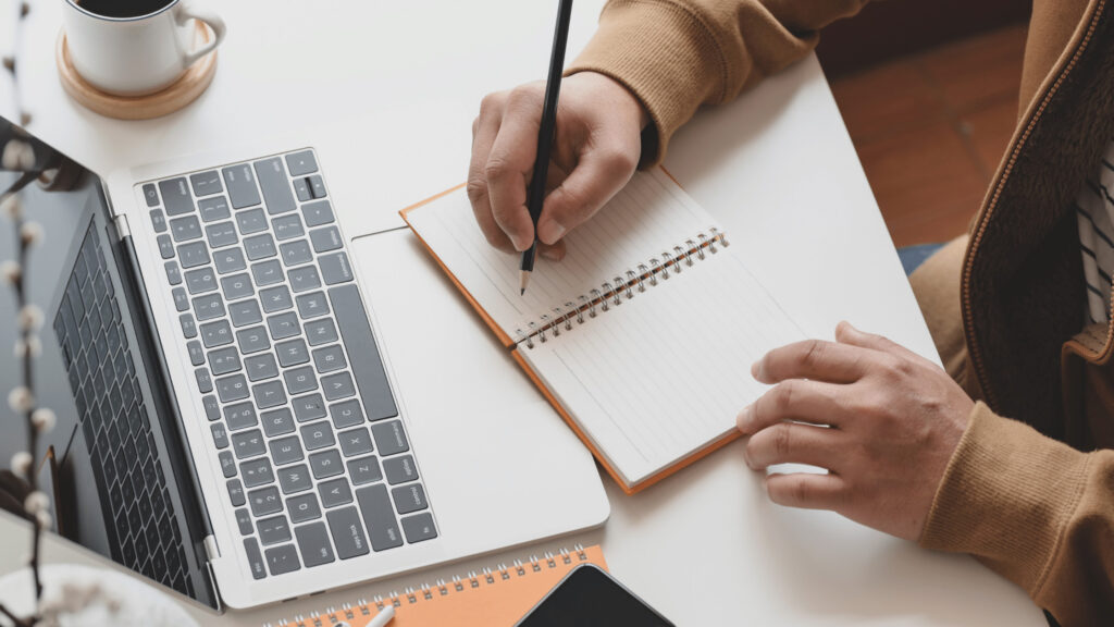 a woman writing with a pencil next to her notebook