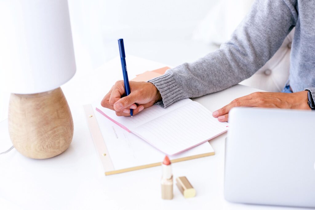 woman writing in a pink notebook